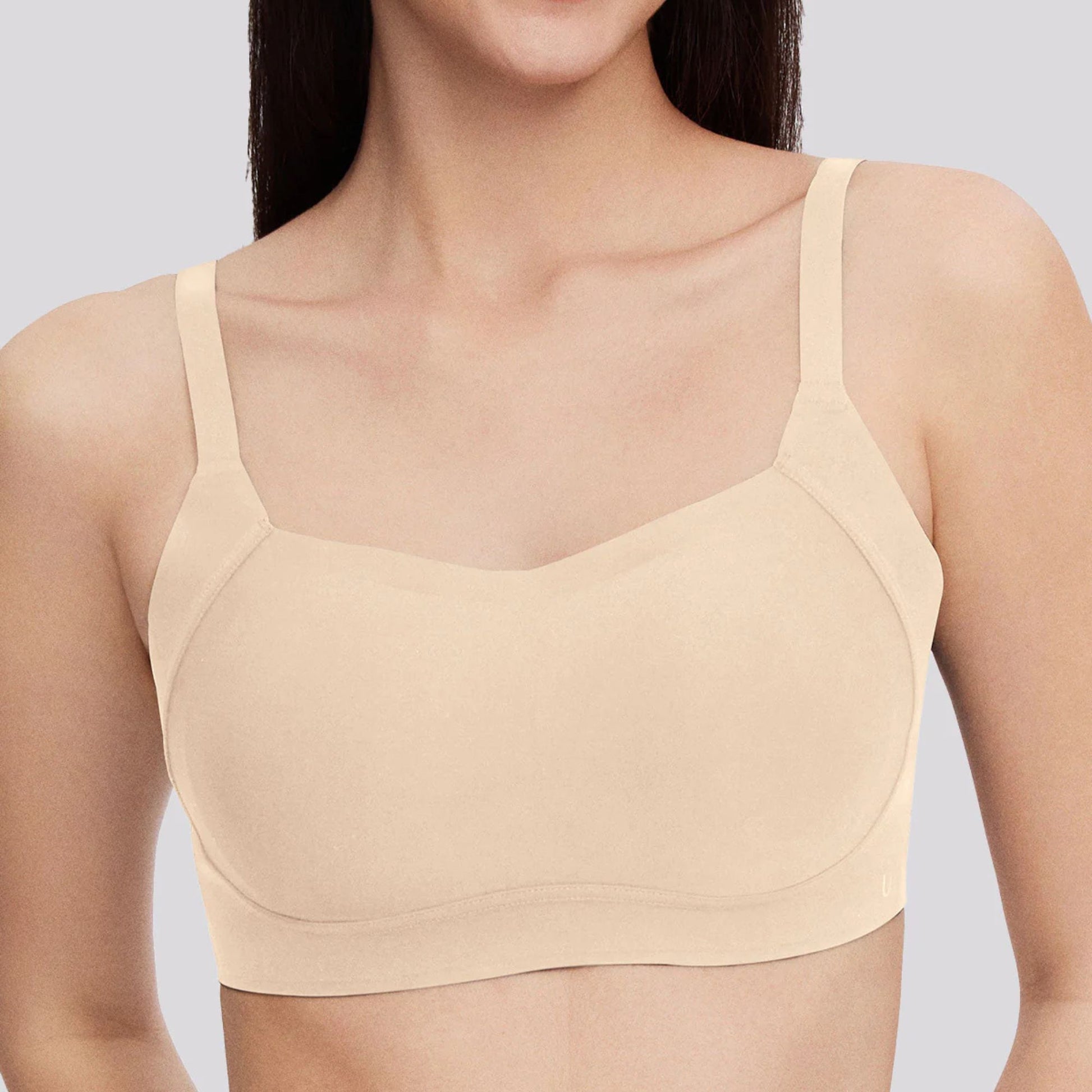 A woman wears the Side Support Back-Hook Bra in Beige by UBRAS