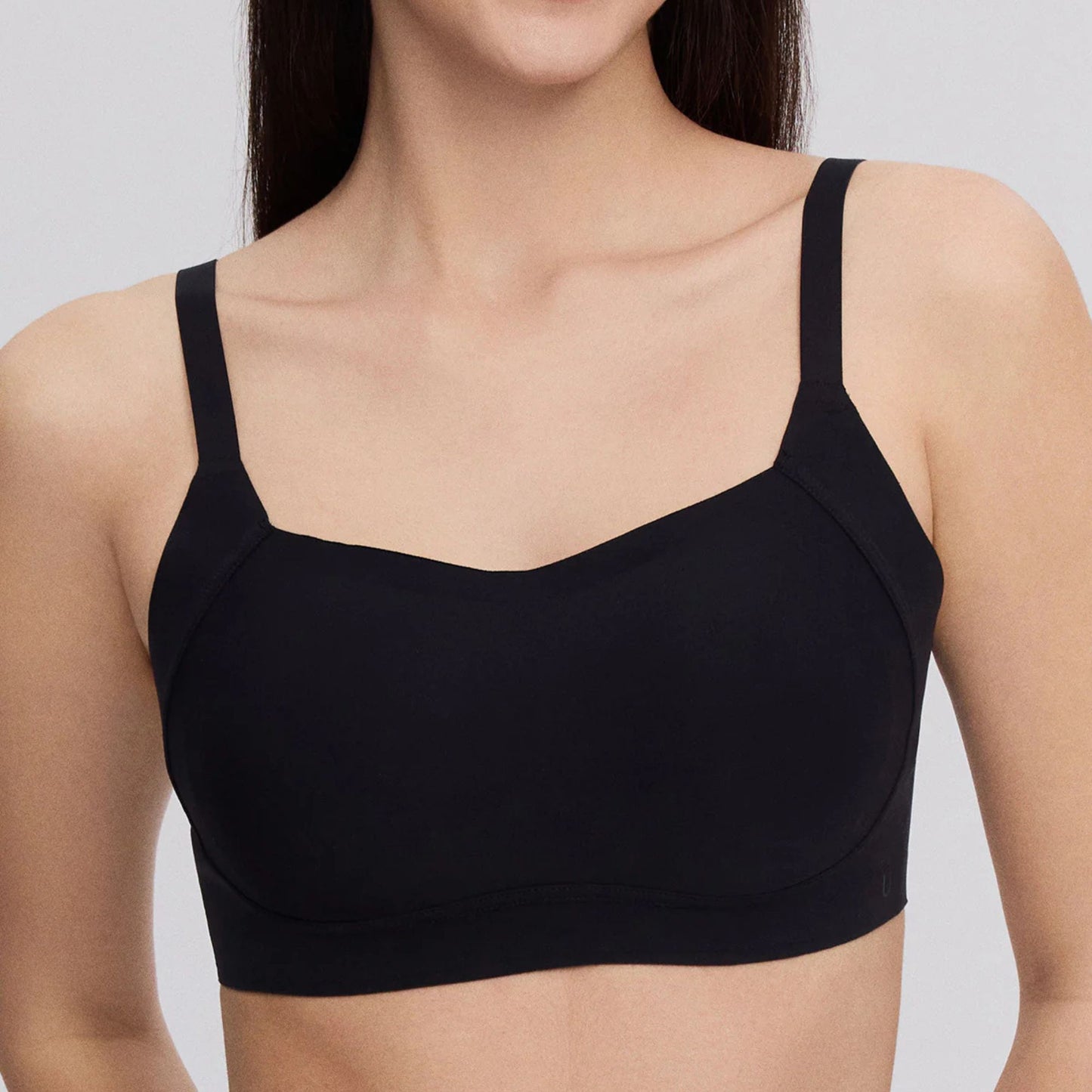 A woman wears the Side Support Back-Hook Bra in Black by UBRAS